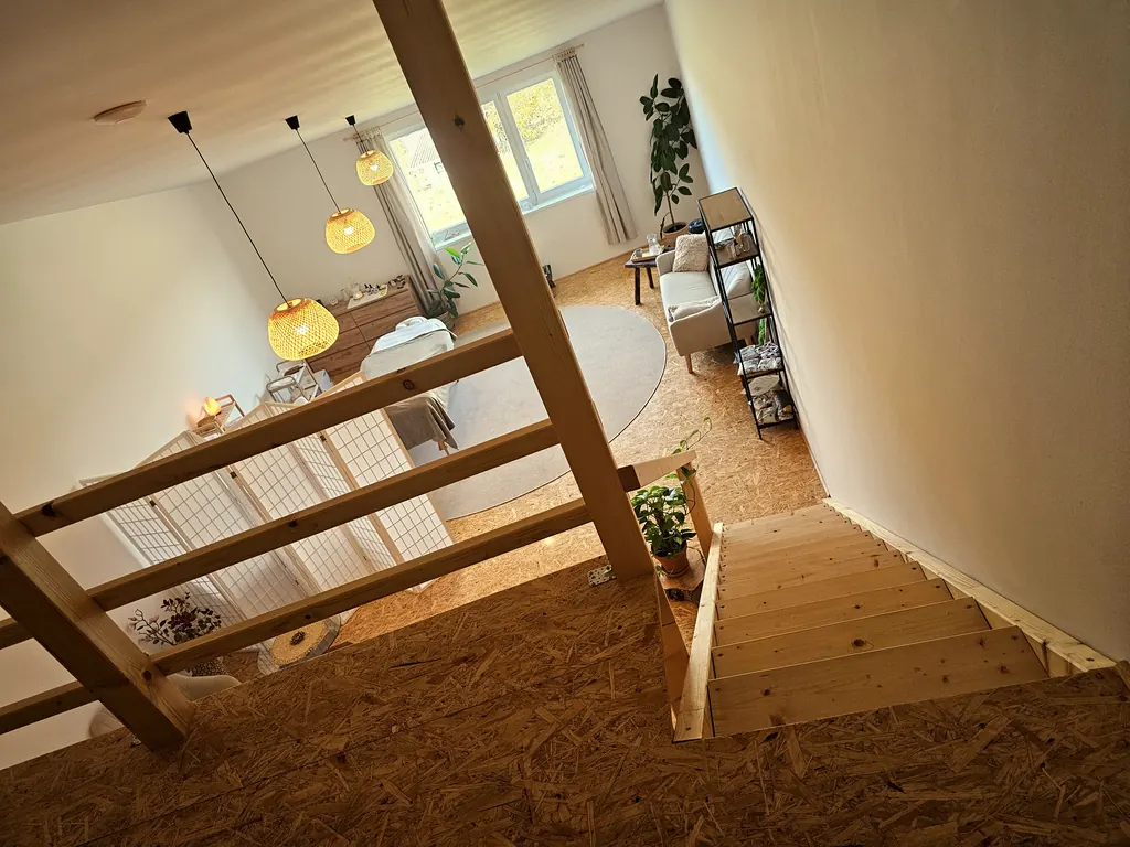 Pohled do studia ARIMA, schody na galerii, kuchyňka a masážní lehátko
